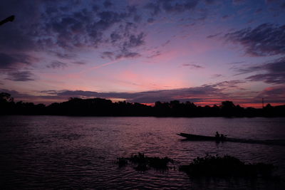 Silhouette man in boat against sky during sunset