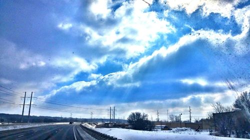 Snow covered landscape against cloudy sky