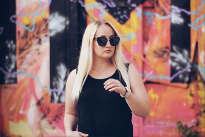 Portrait of young woman wearing sunglasses standing outdoors