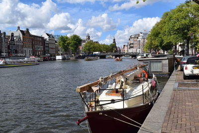 Boats moored on river in city against sky