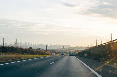 Cars on road seen through windshield during sunset