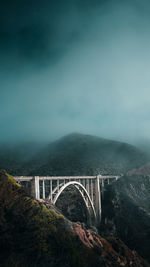 Arch bridge over mountains against sky