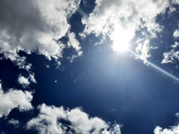 Low angle view of sunlight streaming through clouds