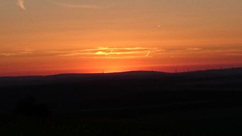 Silhouette landscape against orange sky