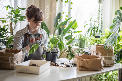 Side view of woman using mobile phone while sitting on table