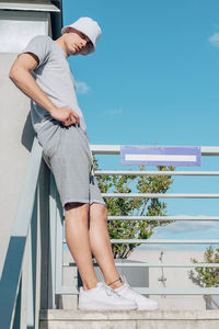 Man sitting on railing against sky