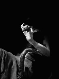 Close-up of man smoking cigarette against black background