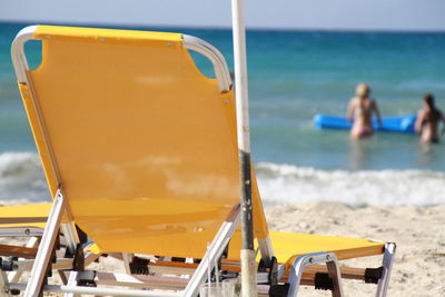 Lounge chairs on beach against sky