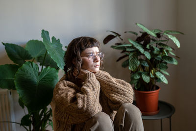 Portrait of young woman standing against wall