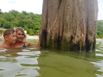 Portrait of smiling woman against trees at shore