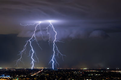 Illuminated cityscape against sky at night