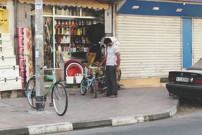 Rear view of man working on bicycle in city