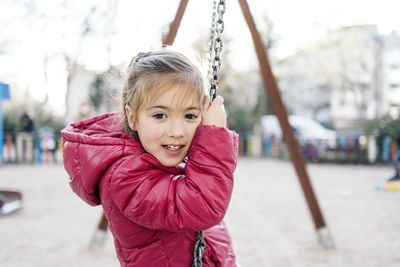 Portrait of girl sitting on swing at park