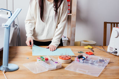 Midsection of woman standing on table at home