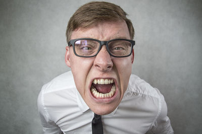High angle portrait of businessman screaming while standing against wall