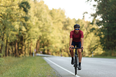 Front view of professional road cyclist dressed in sport clothing racing on bike outdoors. 