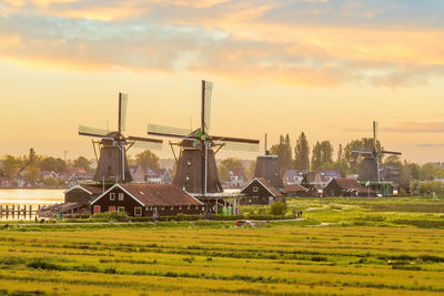 Traditional windmill on field against sky during sunset