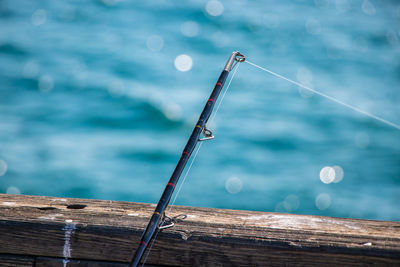 Close-up of fishing rod on wood against sea