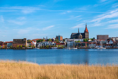 View of buildings by river against cloudy sky