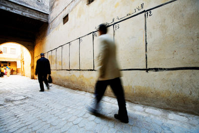 Blurred motion of men walking by election wall