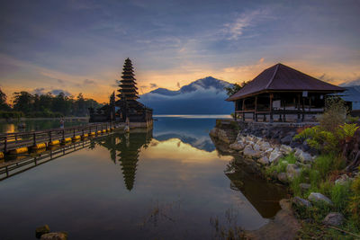 Scenic view of lake by building against sky during sunset