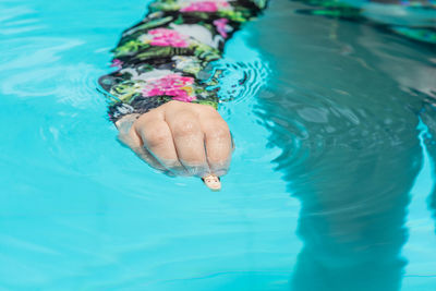 Low section of person hand in swimming pool