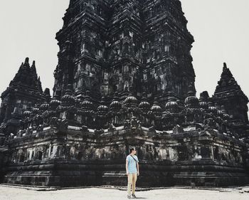 Rear view of woman standing by temple against clear sky