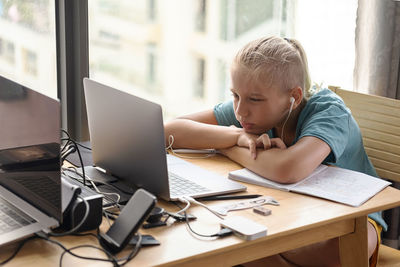 Teenage school boy student wear headphone watch video conference online on laptop. online education