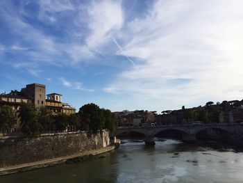 Bridge over river in city against sky