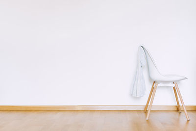 High angle view of chair on hardwood floor against wall