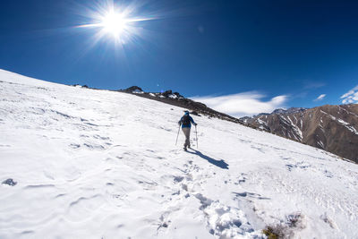 Woman walking on snowcapped mountain against sky