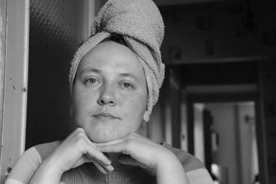 Portrait of woman with hair wrapped in towel sitting at home
