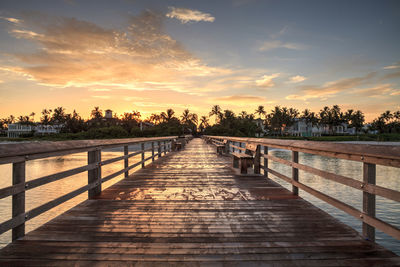 Pier amidst trees against sky during sunset