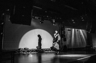 Silhouette people standing on illuminated stage