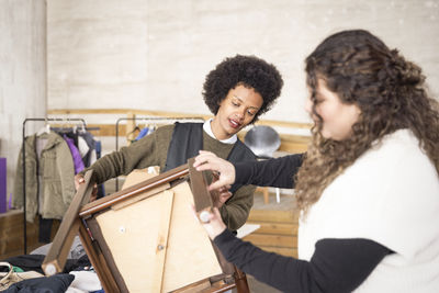 Female workers examining wooden chair at recycling center