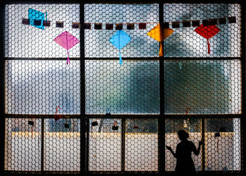 Rear view of people walking on multi colored fence