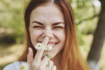Close-up portrait of smiling woman holding flower