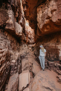 Young woman standing by rock formation