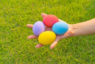 Cropped hand of woman with balloons on grassy field