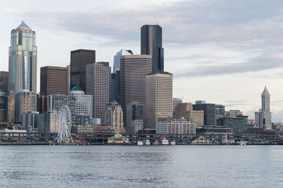 City at waterfront against cloudy sky