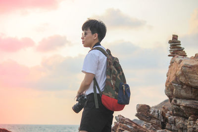 Side view of man standing against sea during sunset