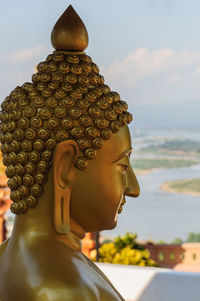 Close-up of buddha statue against sky