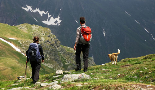 Rear view of people with dog standing against mountains