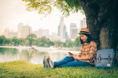 Man using mobile phone while sitting by tree