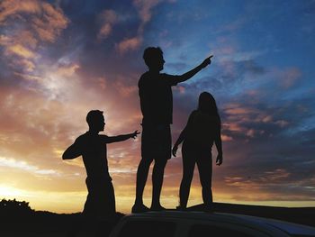 Silhouette friends standing against sky during sunset