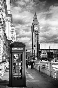 Telephone booth on sidewalk with big ben against sky