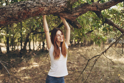 Portrait of smiling young woman standing by tree