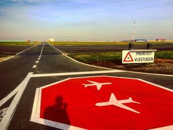 Arrow sign on road against sky