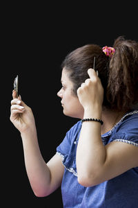 Midsection of woman holding smart phone against black background