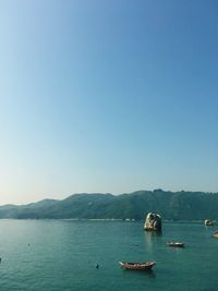 Boats sailing in sea against clear sky